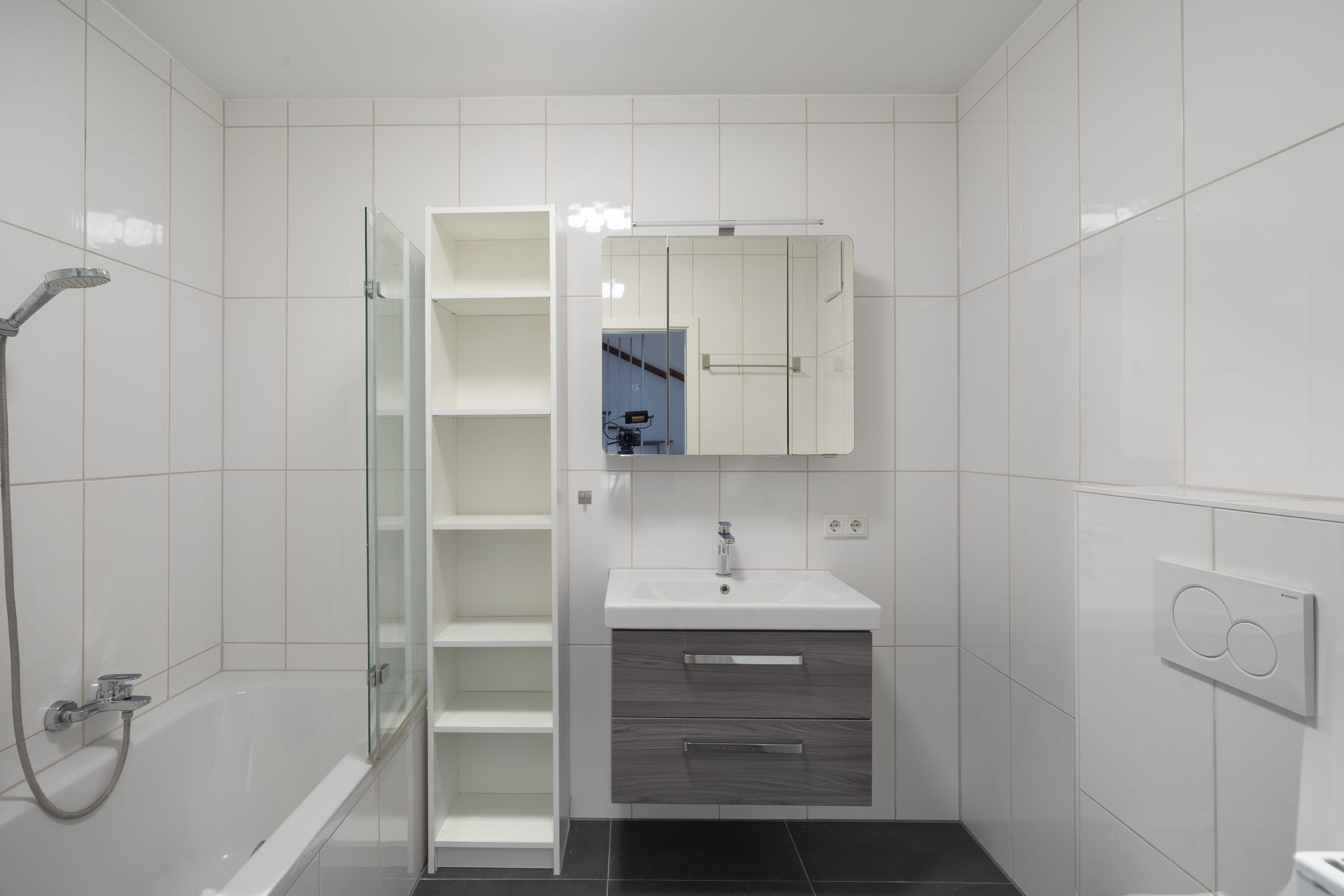 Badezimmer mit weißen Wandfliesen, Waschbecken und Wanne