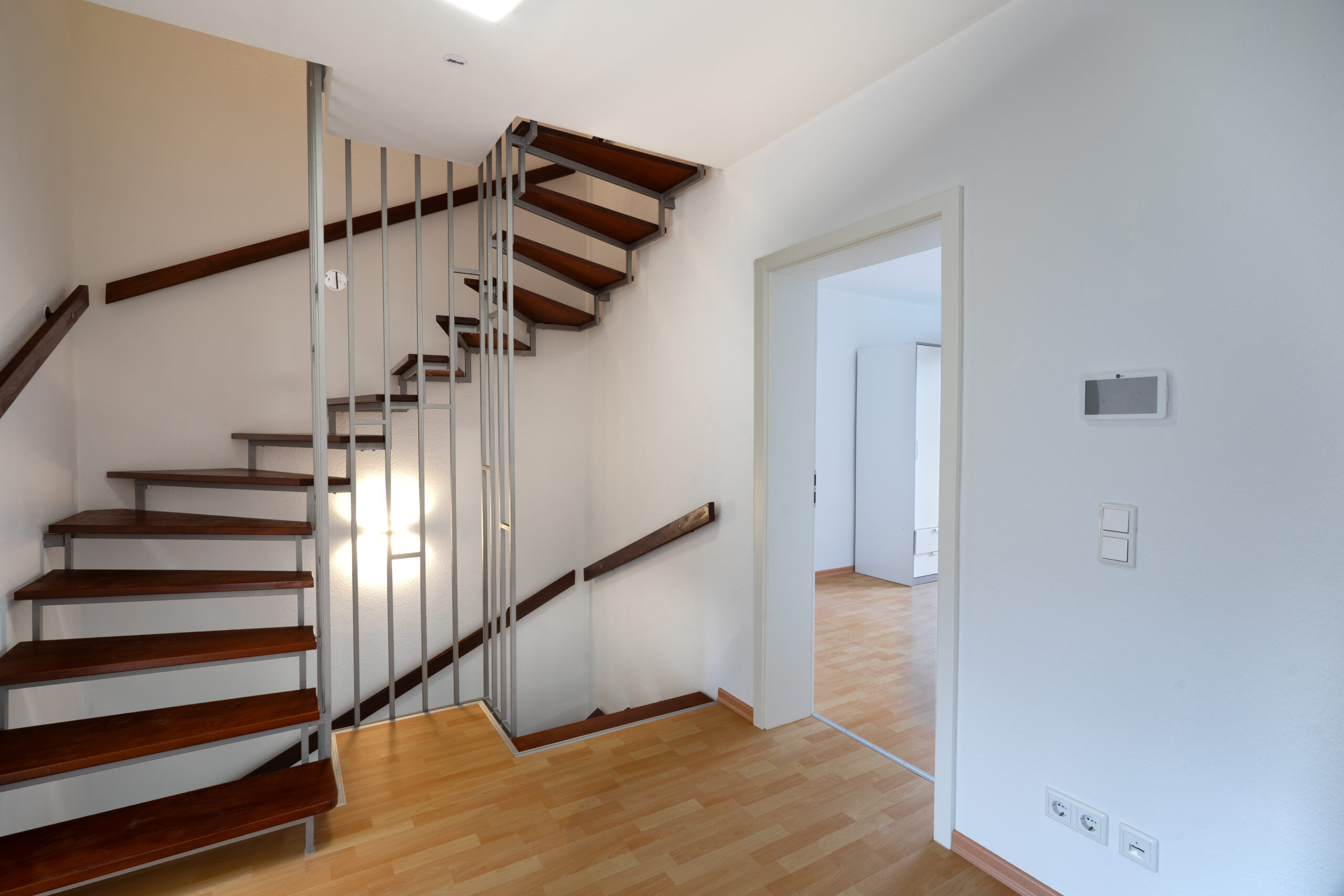 Innenaufnahme einer Holztreppe mit Podest und Zugang zu den angrenzenden Räumen