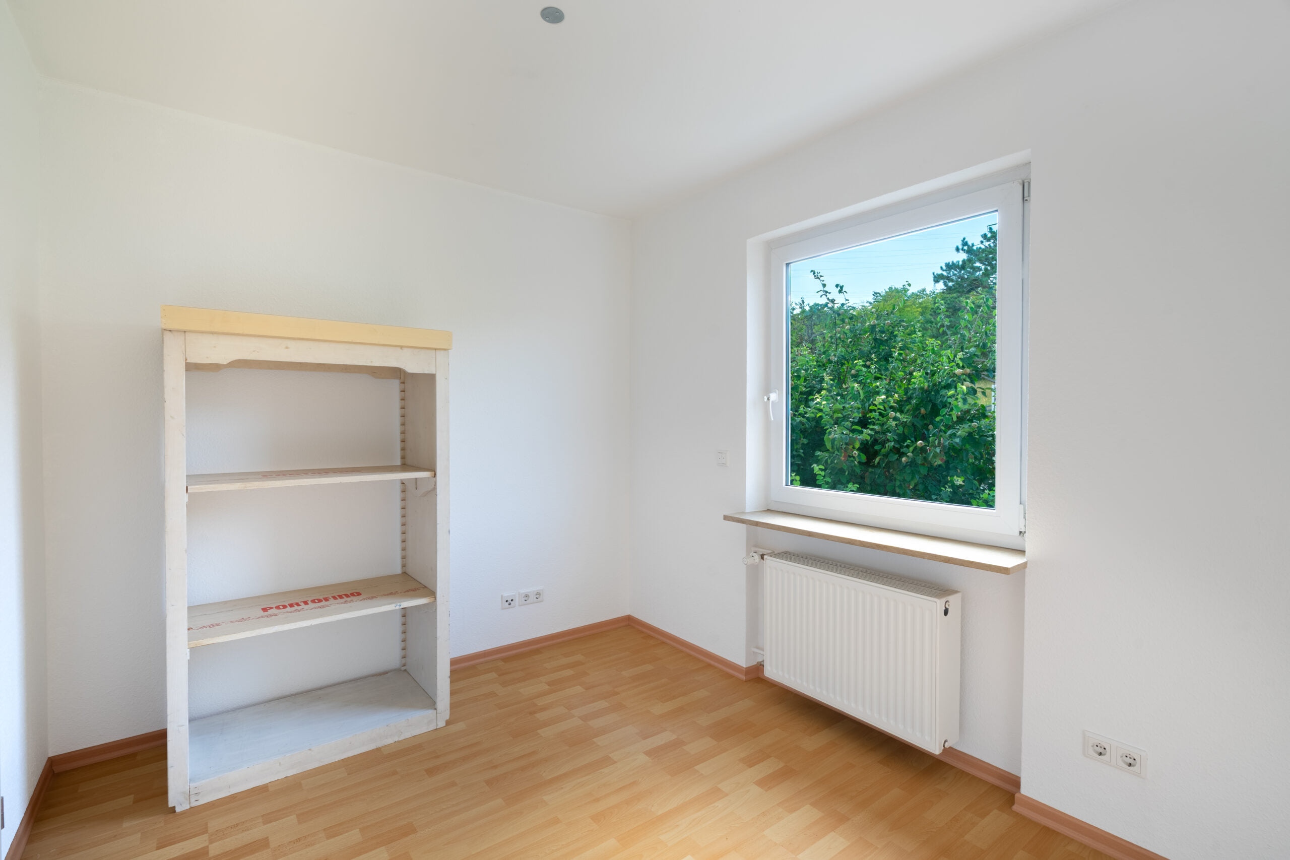 Leerer Raum mit Holzregal, Heizkörper und Fenster
